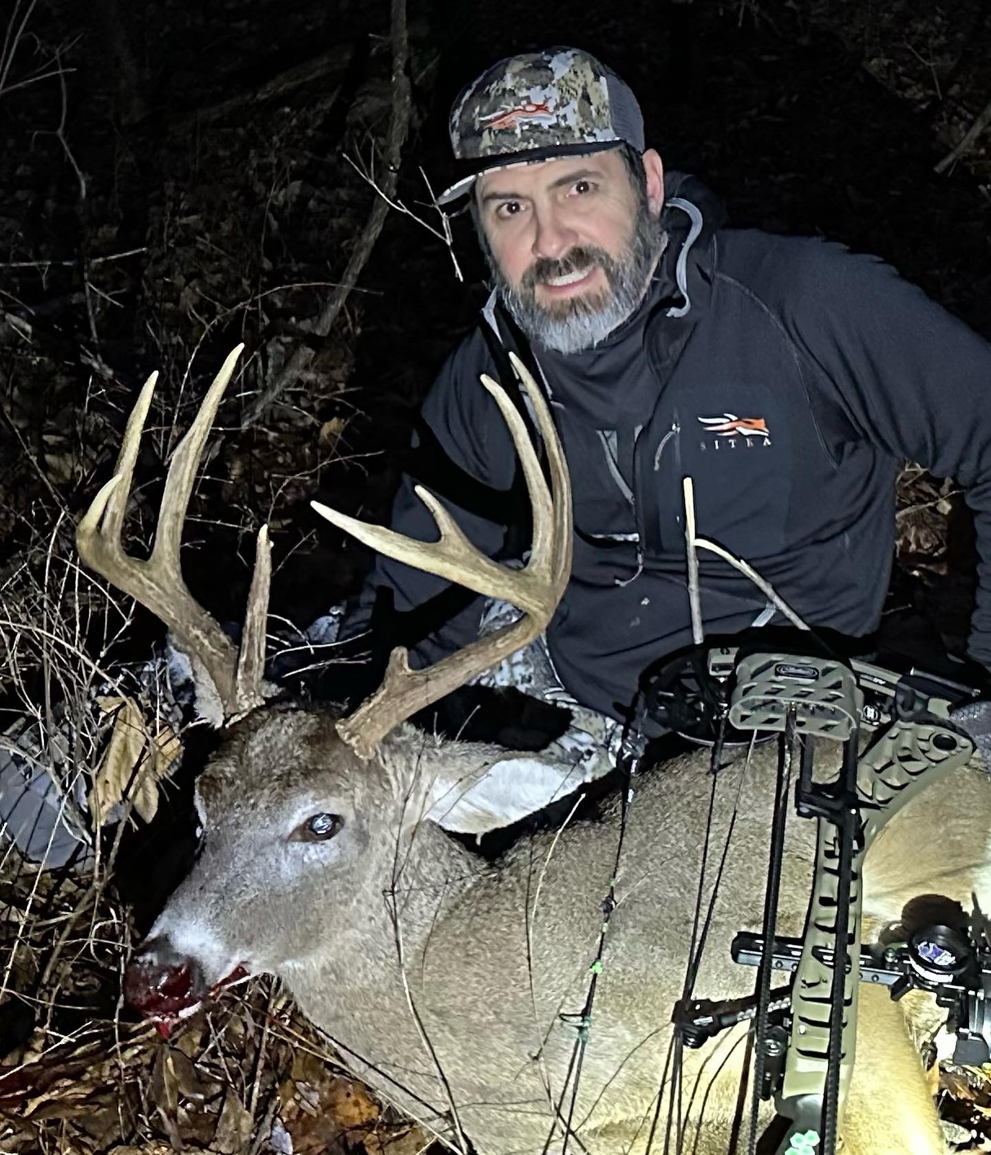 Successful archery hunter with trophy whitetail buck at night