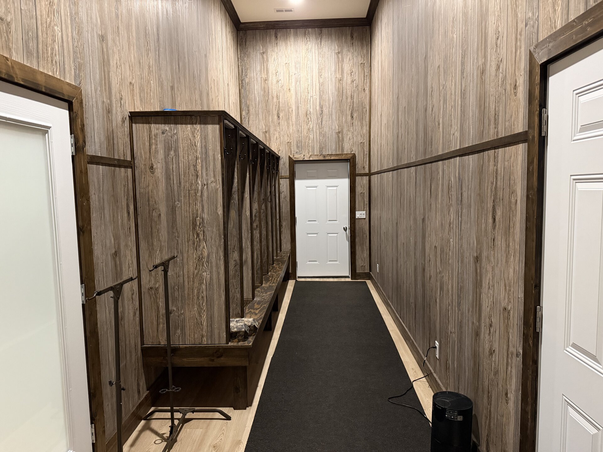 Mudroom with built-in wooden lockers, bench seating, and gear stands