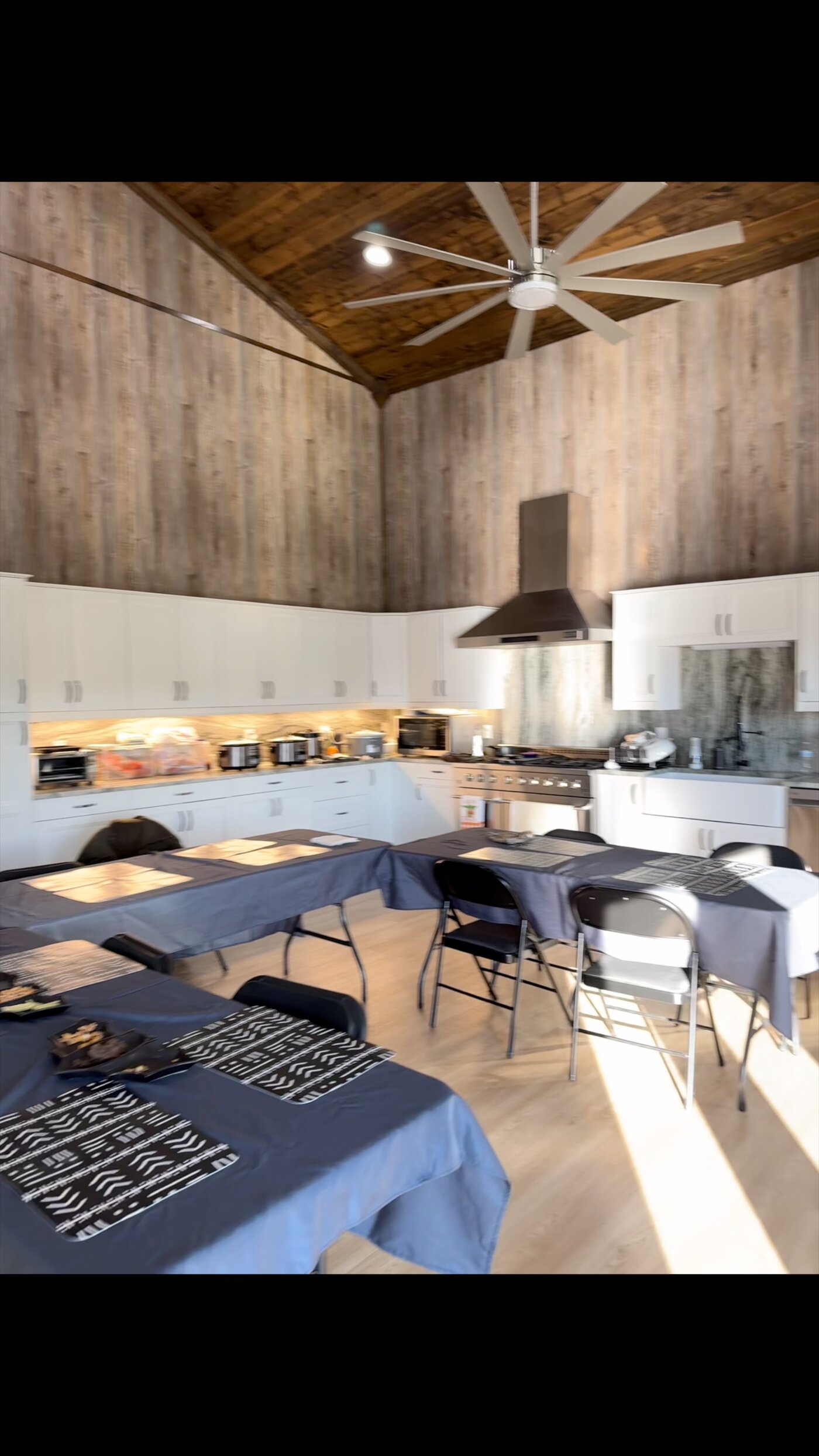 Bright chef's kitchen with white cabinetry, stainless appliances, and a long family-style dining table set for the group